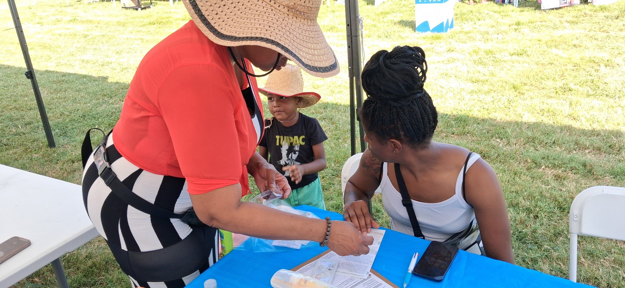 Founder Cjuna Cole distributing wellness essentials to a mother and child at the Pagedale Family Festival